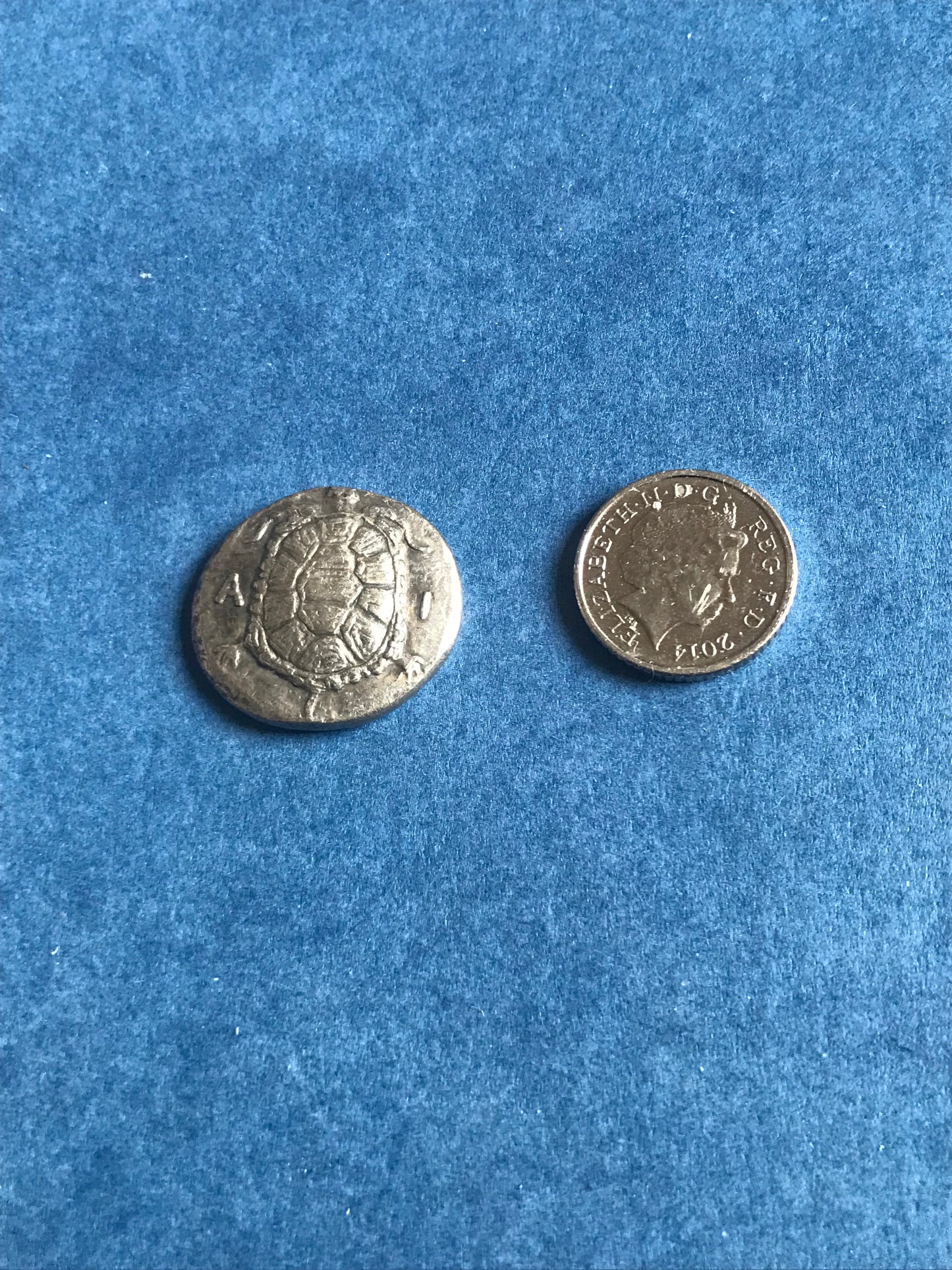 Two silver coins on a blue textured surface