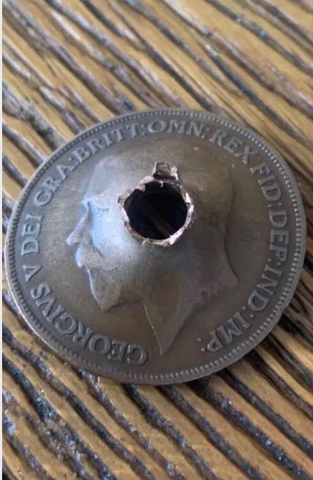 World War One Dated 1914 Coin damaged by Shrapnel on a wooden background