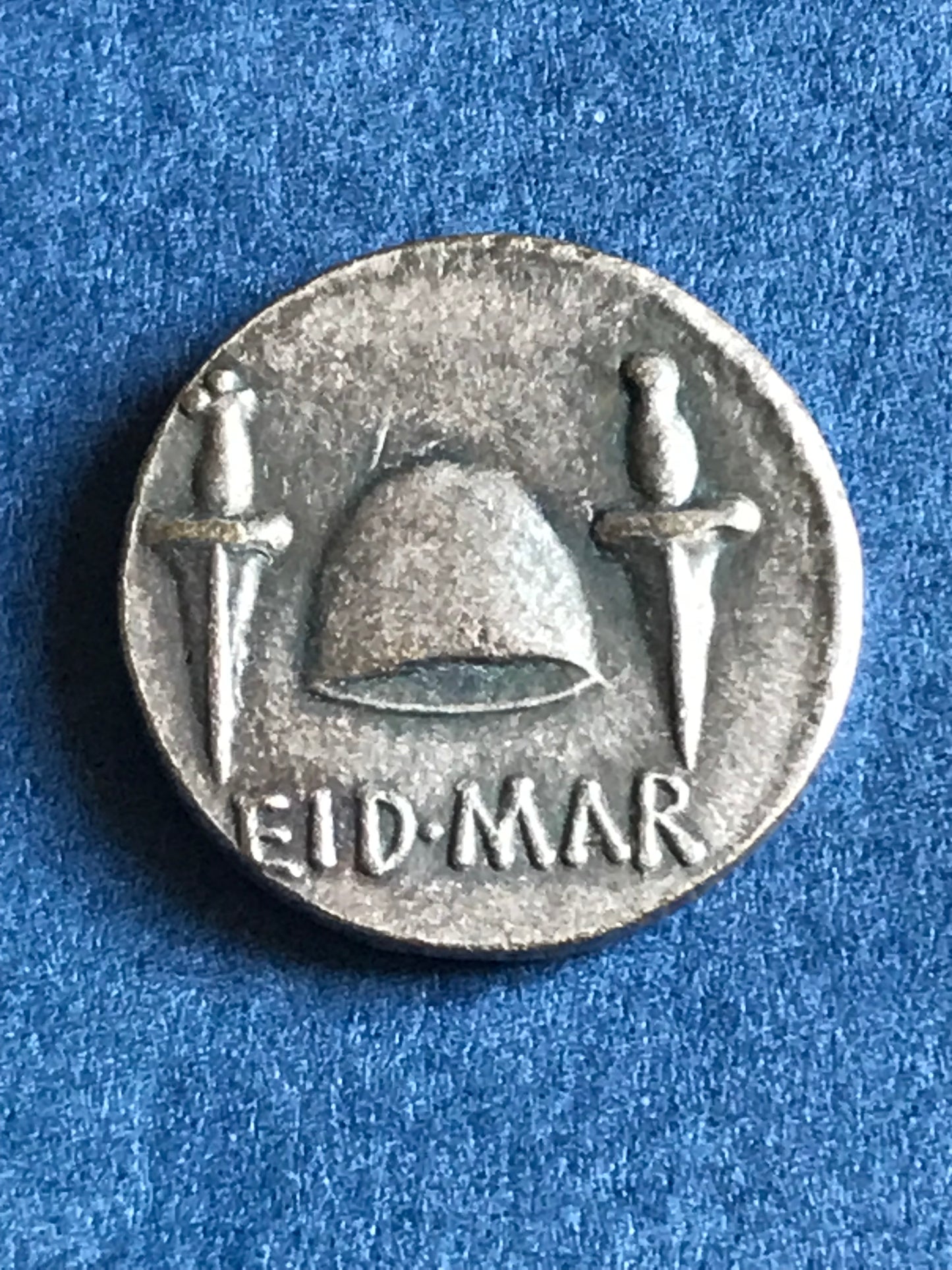 Silver coin with a helmet and sword design on a blue background