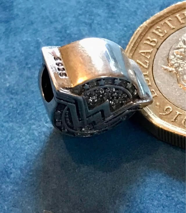 Genuine 925 Silver Wonder Woman charm next to a British coin on a blue background