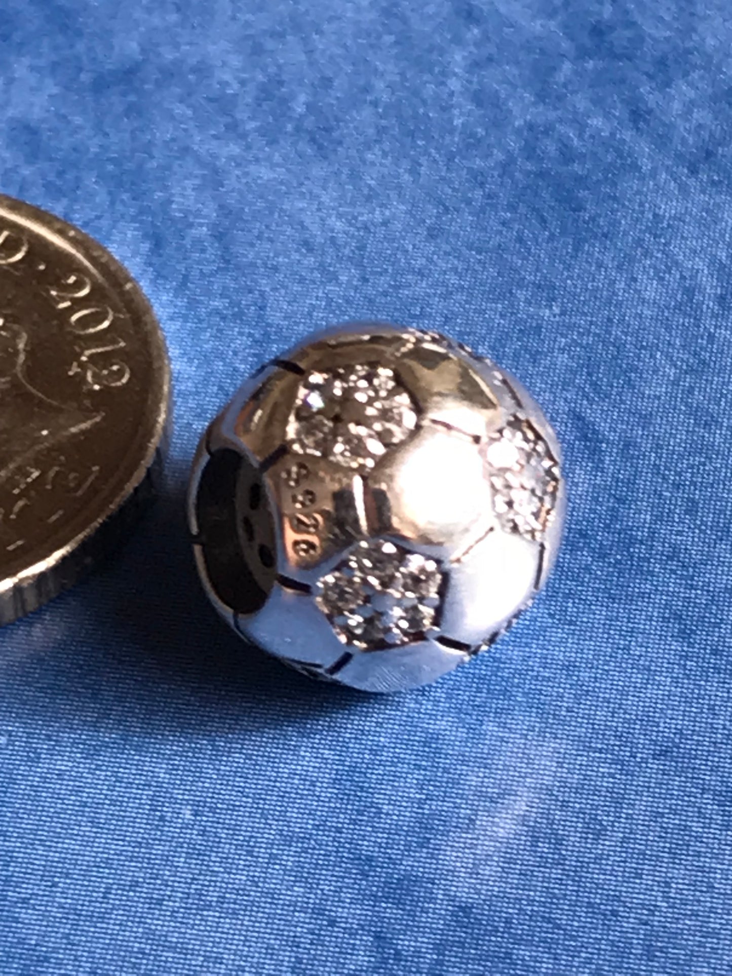 Silver Football charm on a blue fabric background