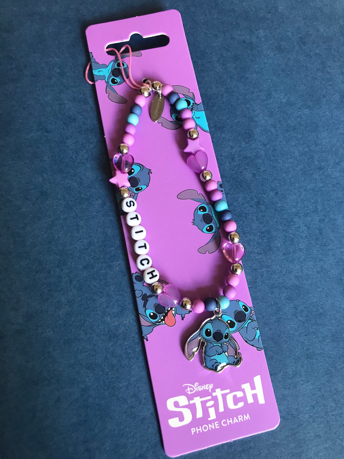 Disney Stitch phone charm on a purple card with 'Stitch' branding against a dark blue background