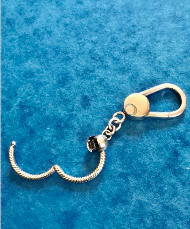 Gold and silver keychain for charms on a blue textured background
