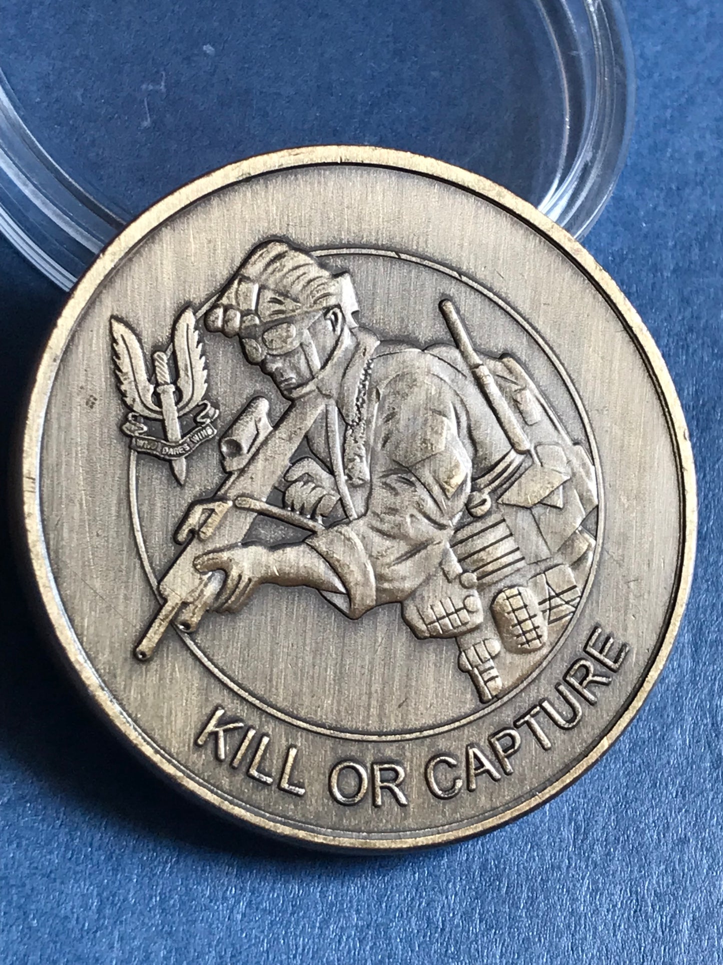 Silver coin with a military-themed design on a blue background