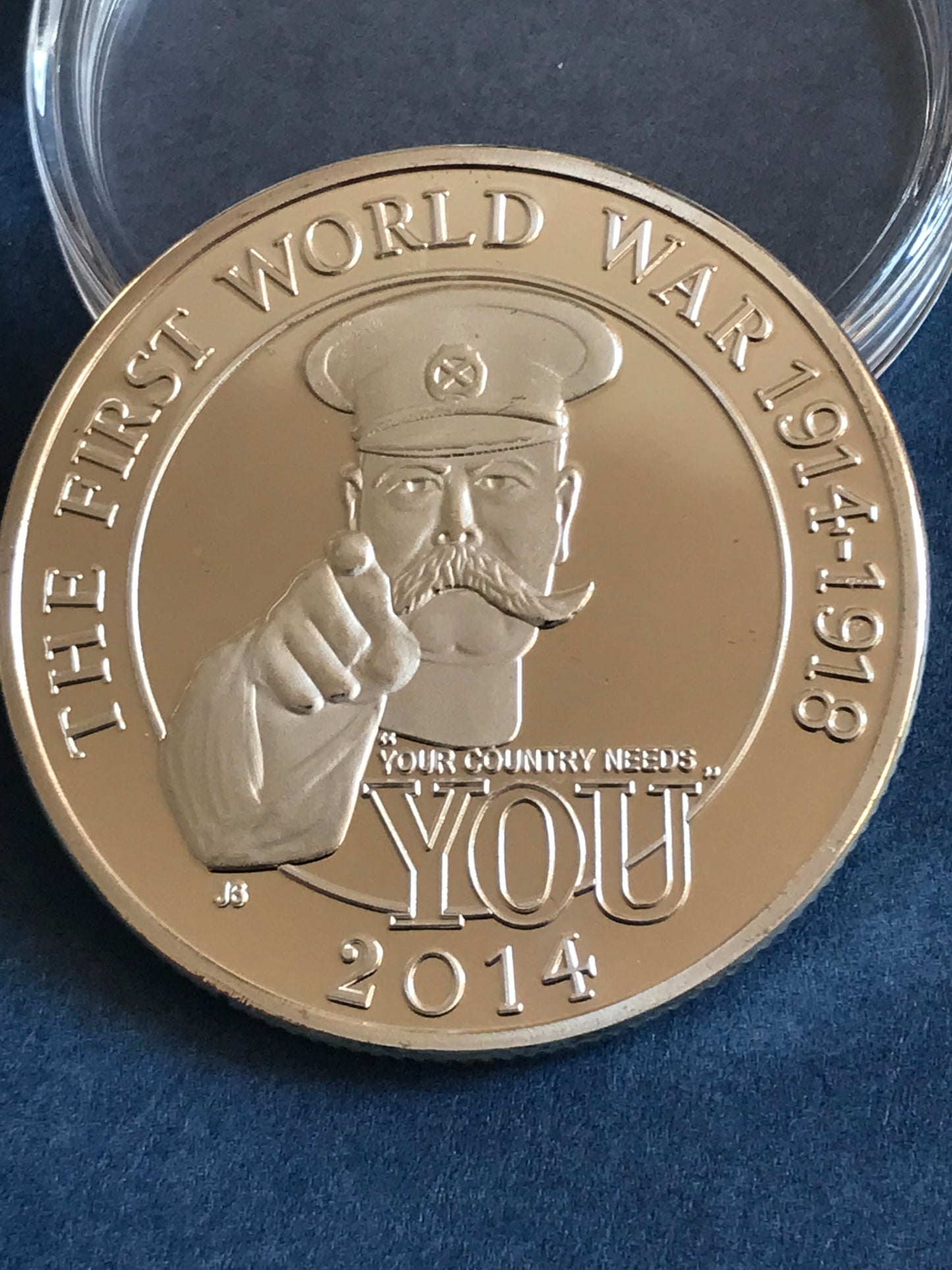 Gold coin commemorating World War I with a portrait and text on a blue background