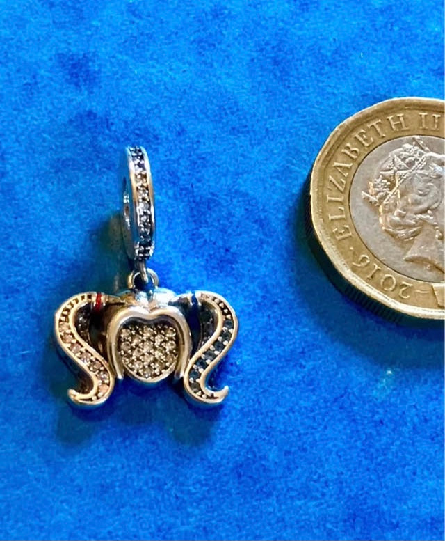 Genuine 925 Silver Harley Quinn charm next to a British two-pound coin on a blue background