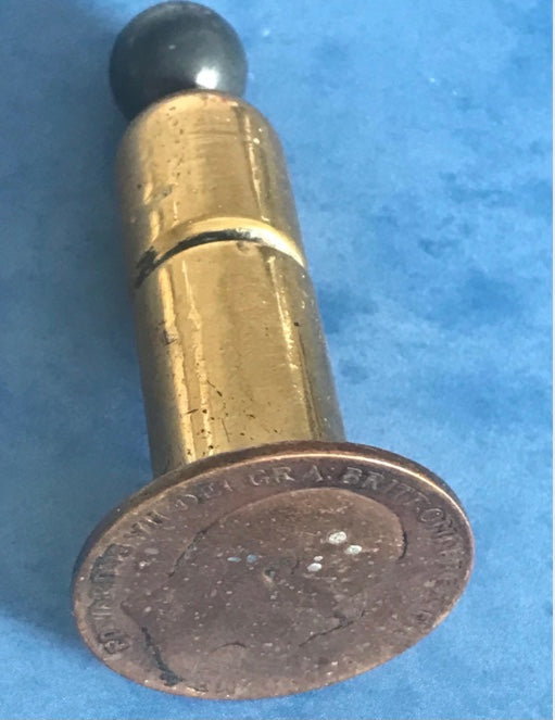 Vintage 1908 dated World War One brass needle holder on a blue background