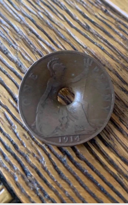 World War One Dated 1914 Coin damaged by Shrapnel on a wooden background
