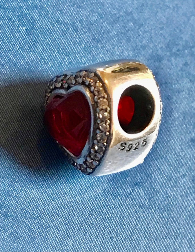 Genuine 925 Silver Red Heart Charm with red stone on a blue fabric background