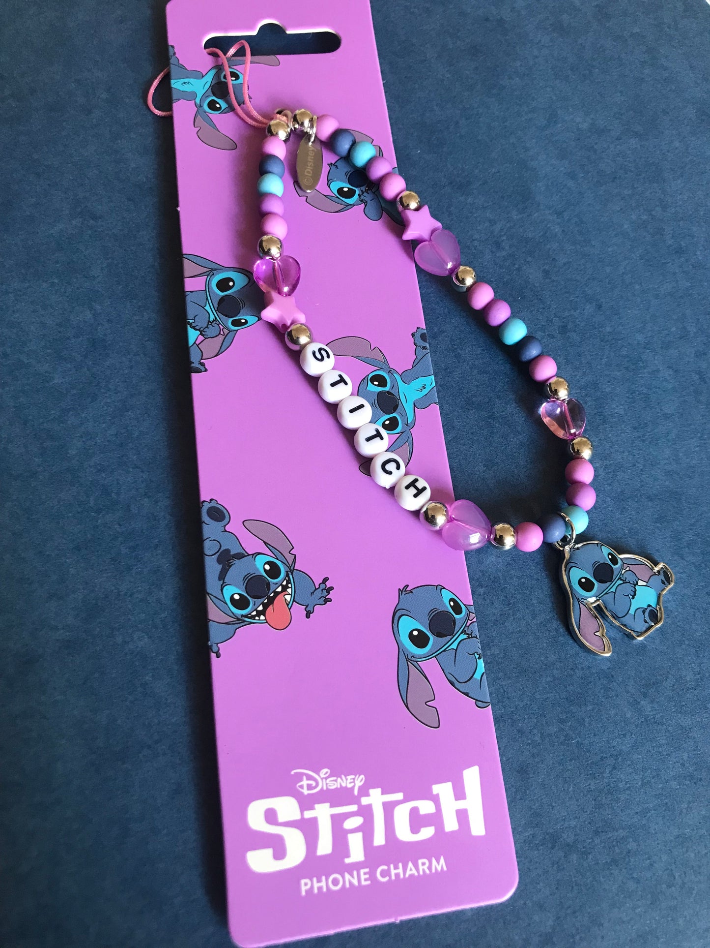 Disney Stitch phone charm on a purple card with Stitch illustrations against a dark blue background