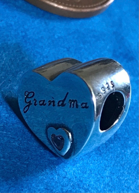Silver heart-shaped charm with 'Grandma' engraving on a blue background
