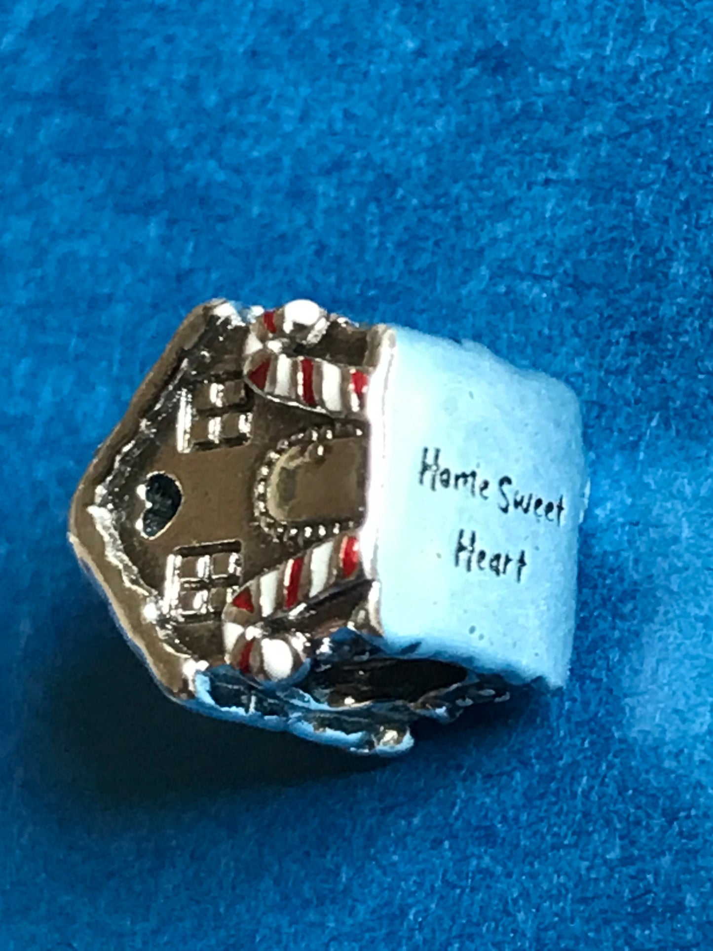 Silver charm with 'Home Sweet Home' text on a blue background