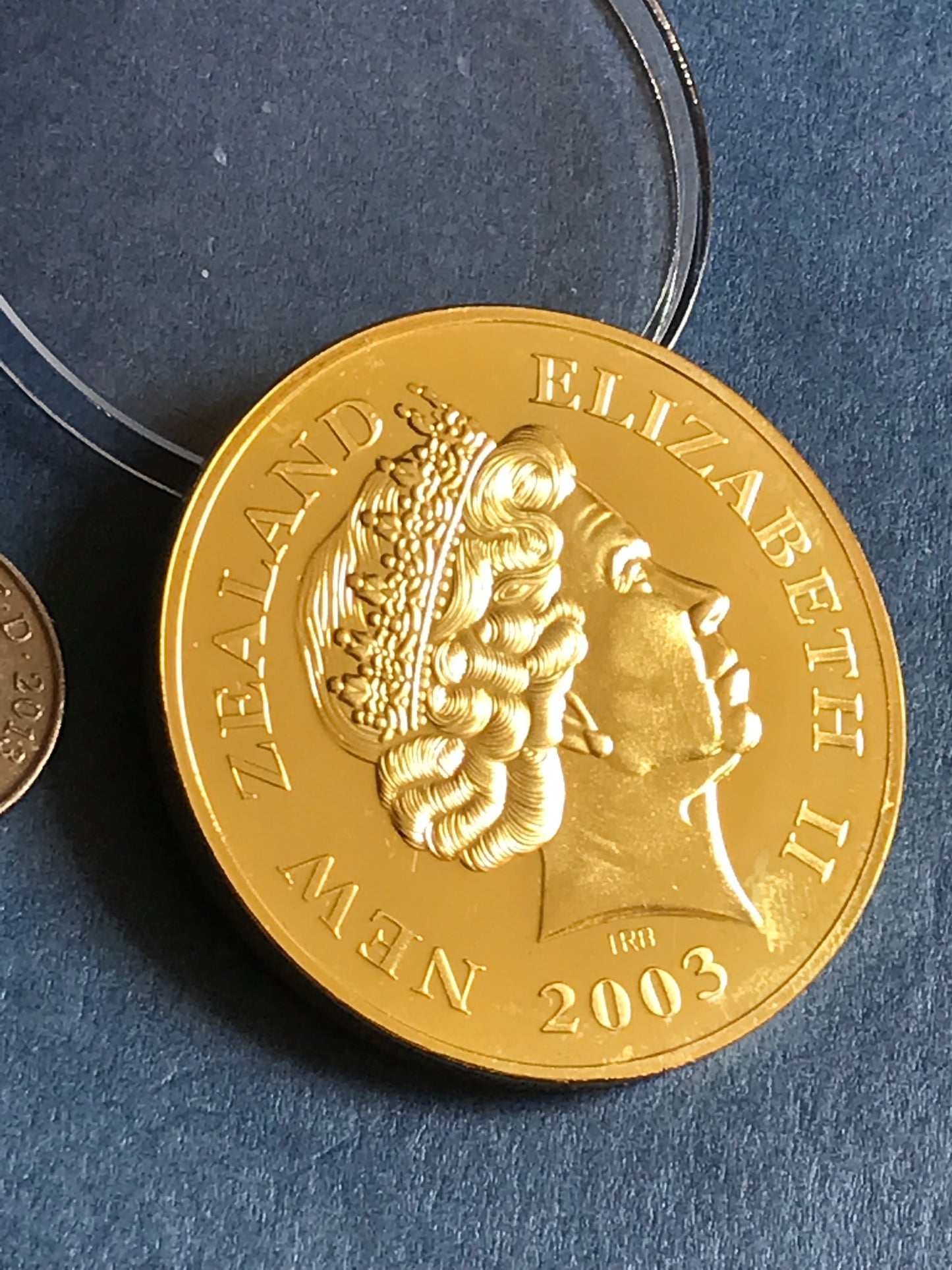 Gold coin with 'Elizabeth II' and 'New Zealand' text on a dark blue background
