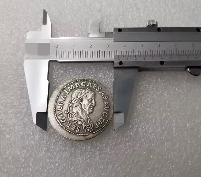 Silver coin with engraved face held by calipers against a gray background