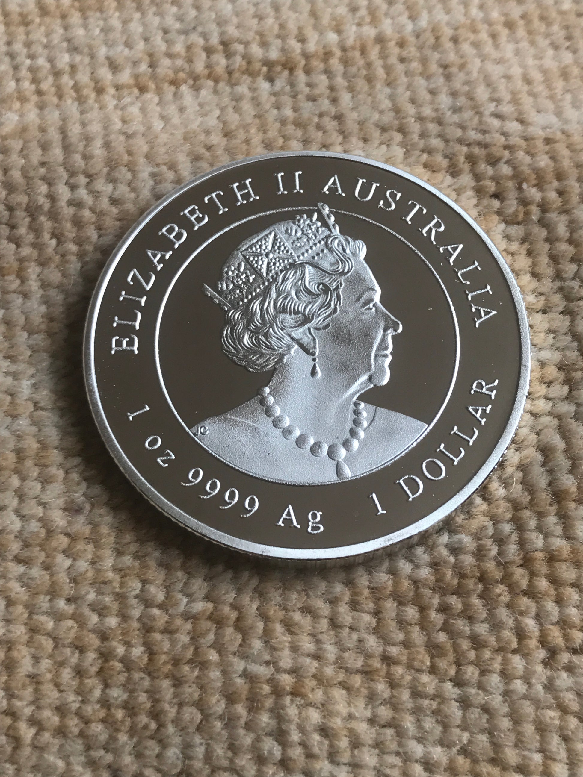 Silver coin with engraved design on a textured fabric background