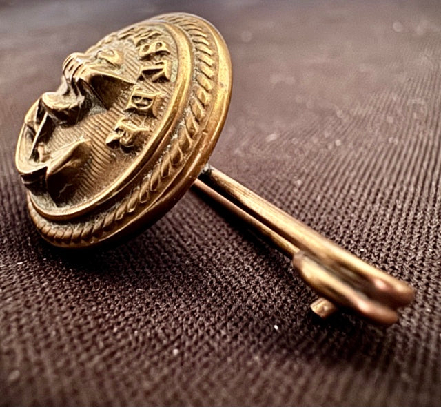 World War Two Trench Art Sweetheart Broach Brass Button on a textured brown background