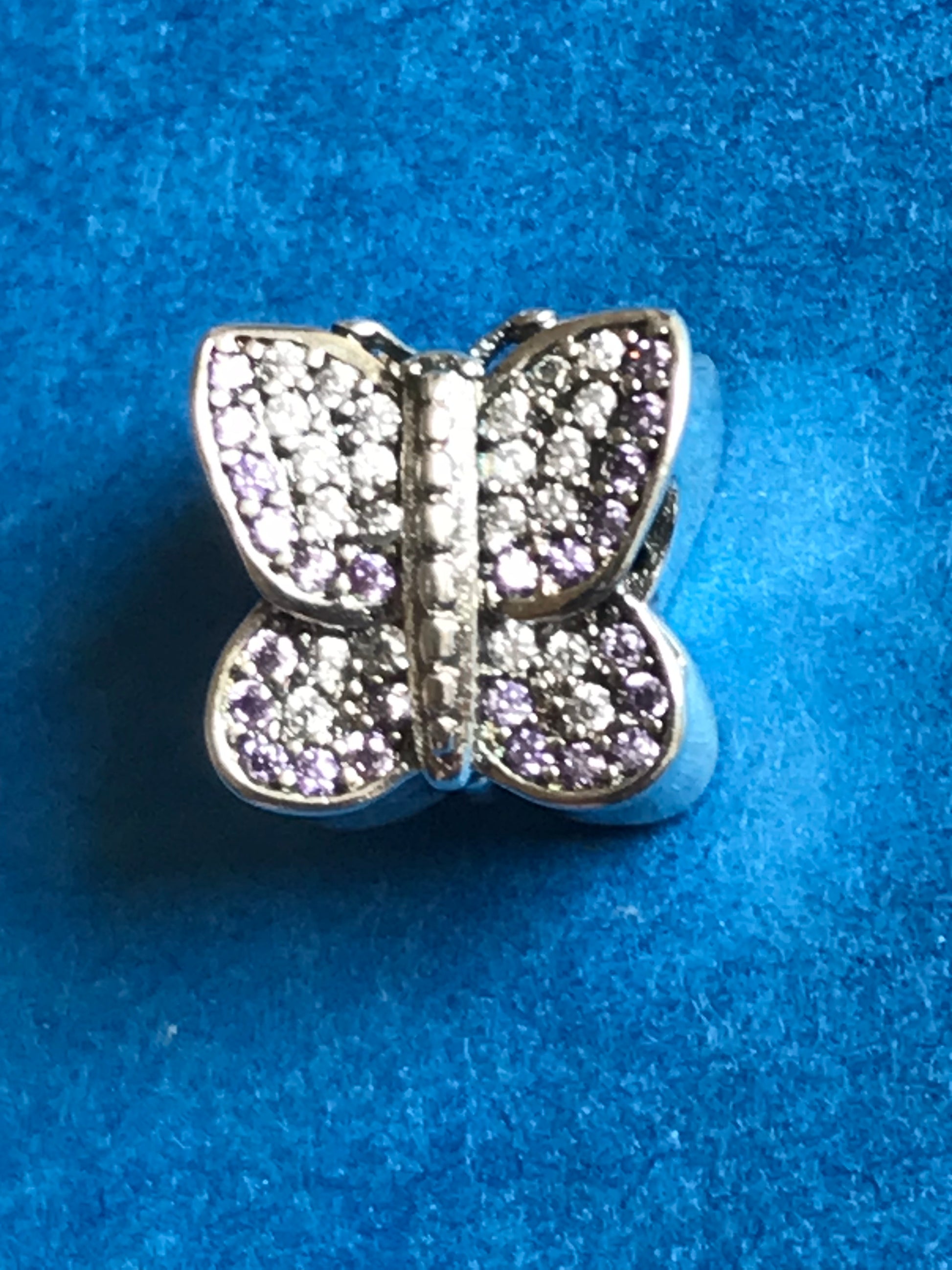Butterfly-shaped charm with embedded stones on a blue background