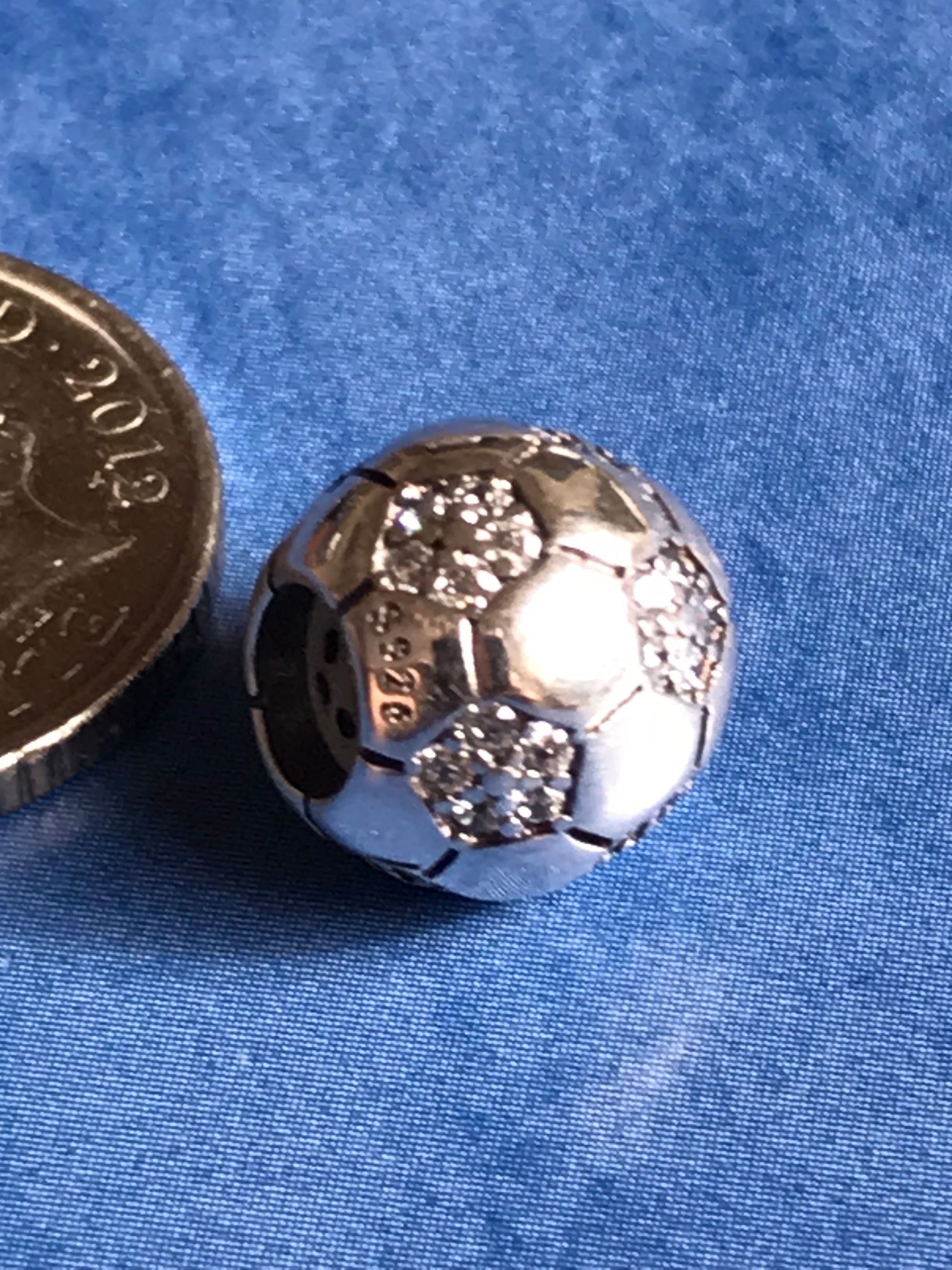 Silver Football charm on a blue fabric background