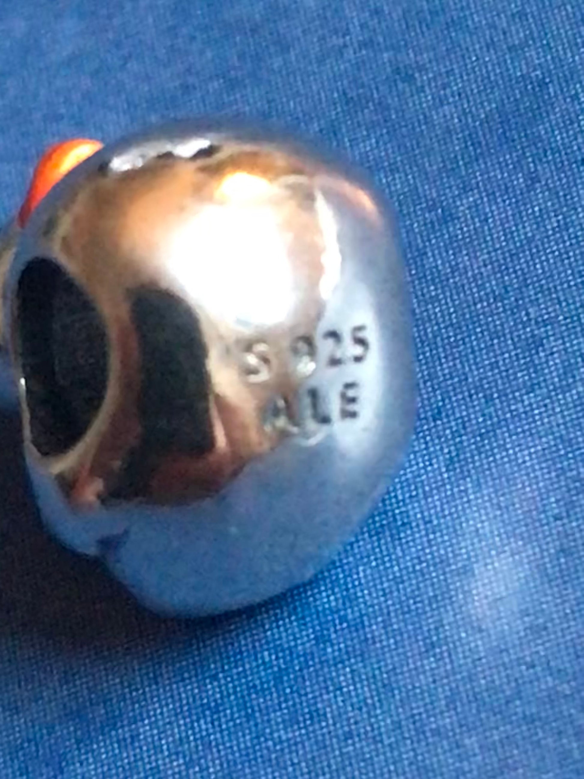 Silver Duck charm with '925' stamp on a blue fabric background