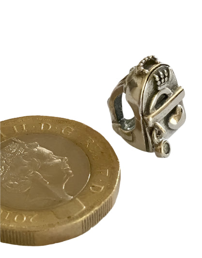 Silver charm next to a British pound coin on a white background for charm bracelet 925 silver