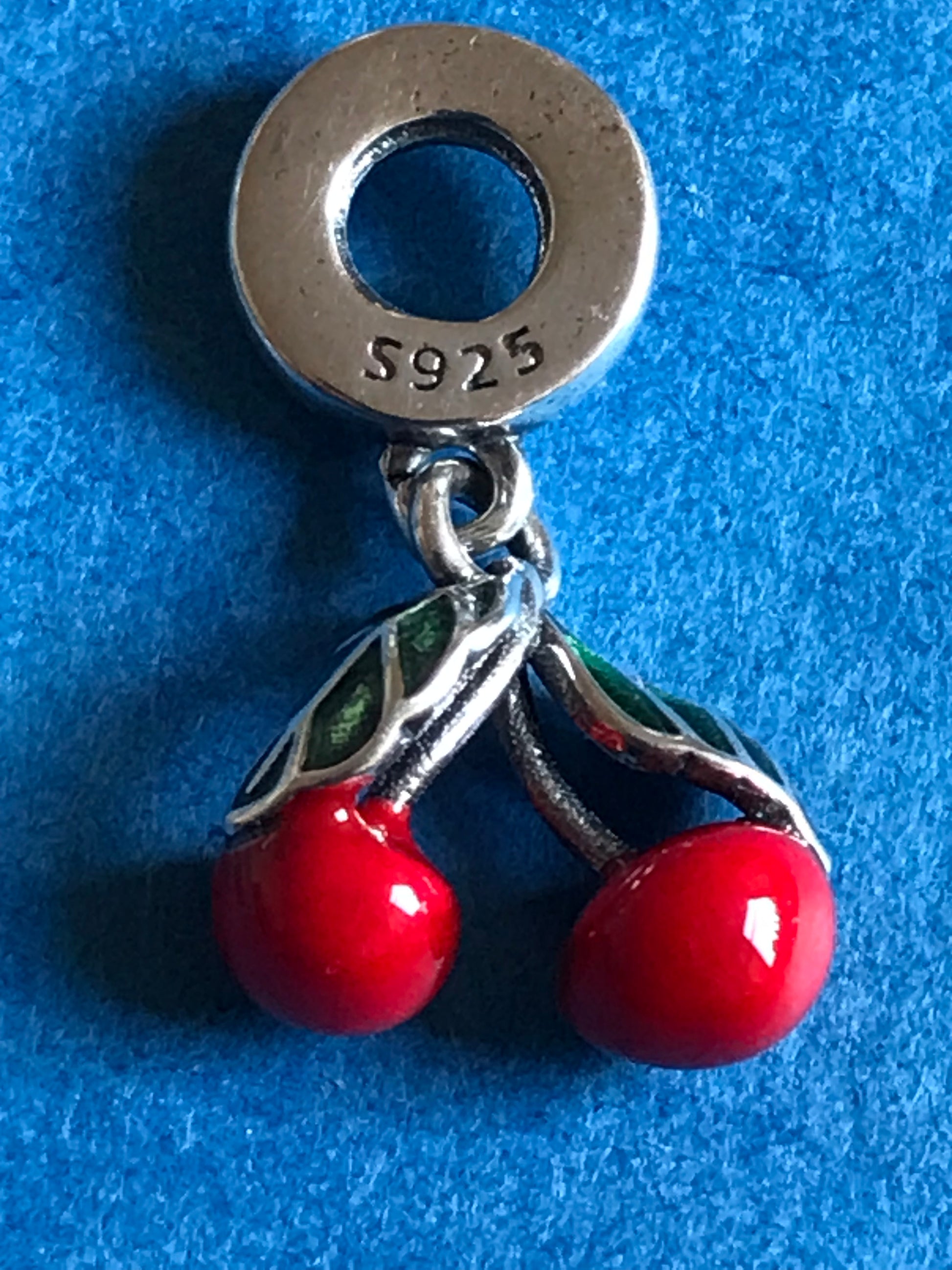 Silver charm with red beads on a blue background