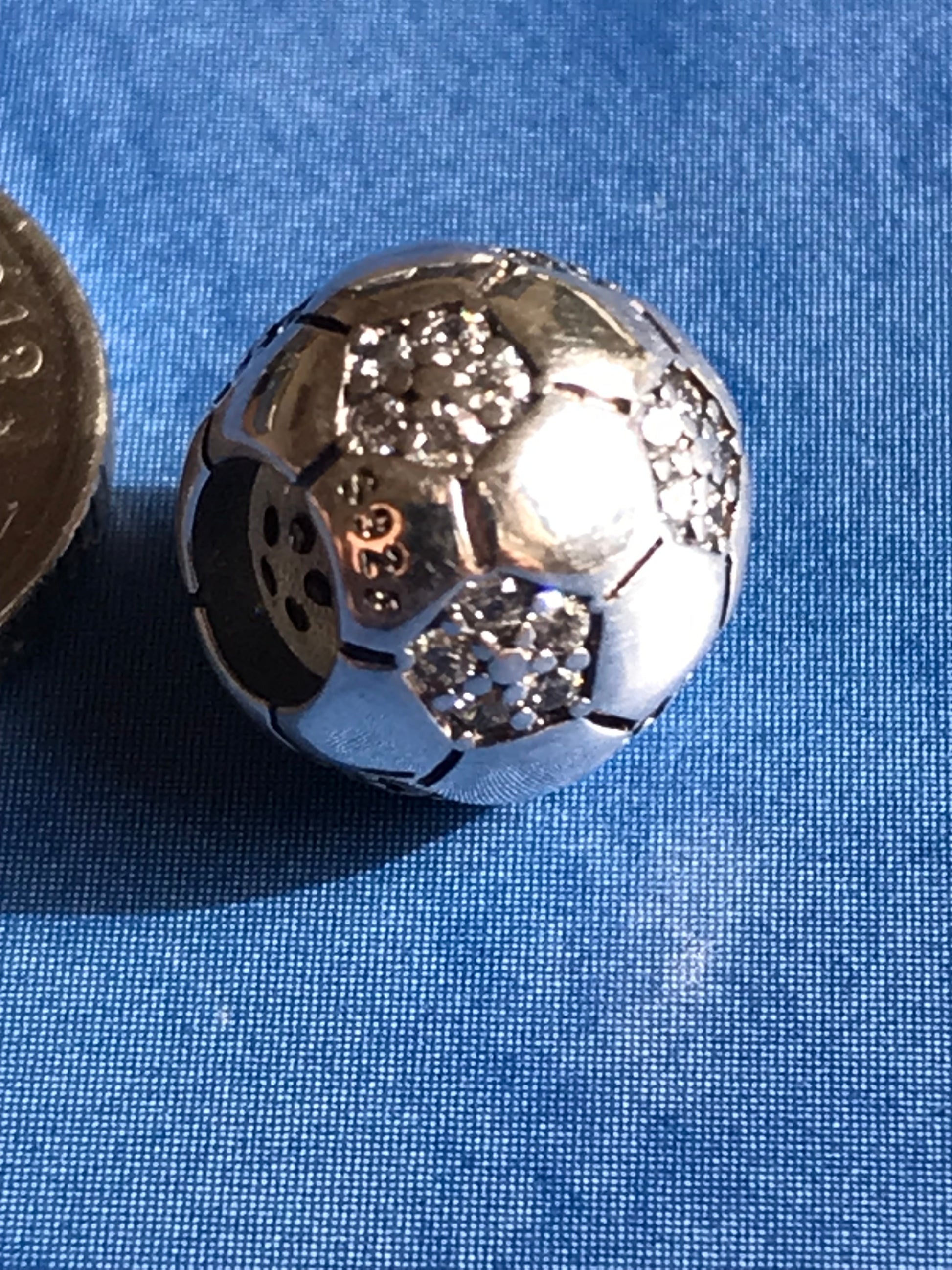 Close-up of a Silver Football charm with gemstones on a blue background 925 silver 