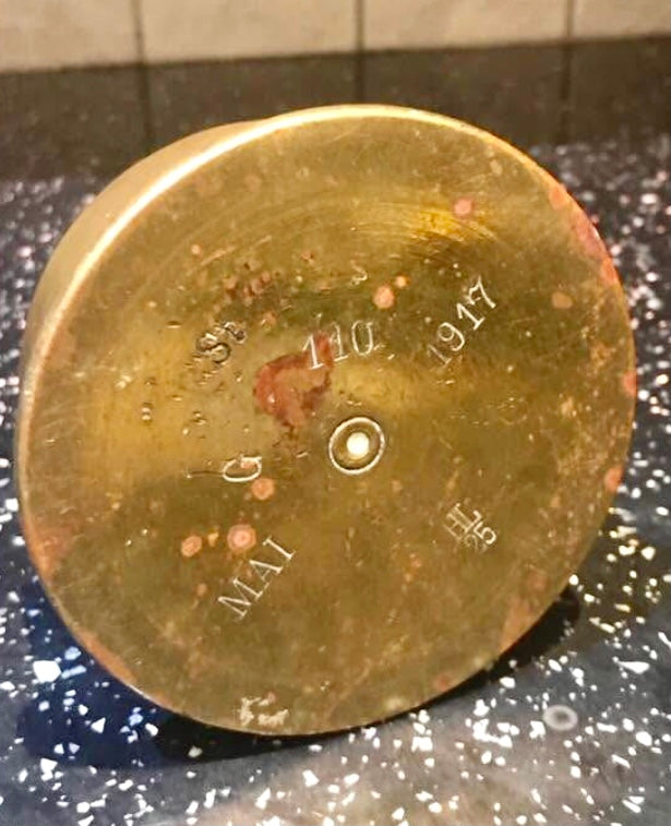 Brass WW1 Trench Art Ashtray with engraved text on a dark speckled surface