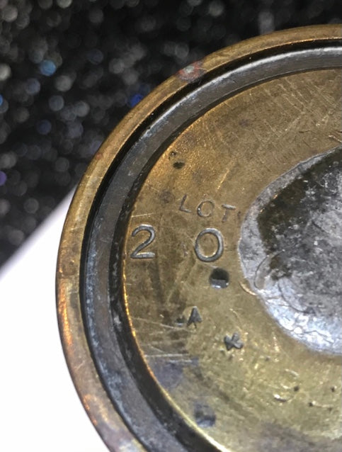 Close-up view of a brass World War Two Trench Art Vase with inscriptions on a kitchen work surface