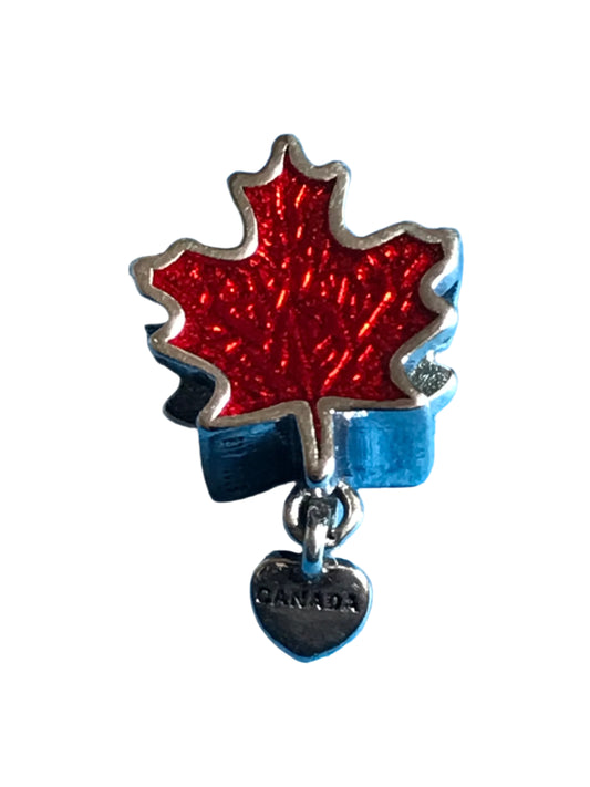 Red maple leaf charm with silver border on a blue background