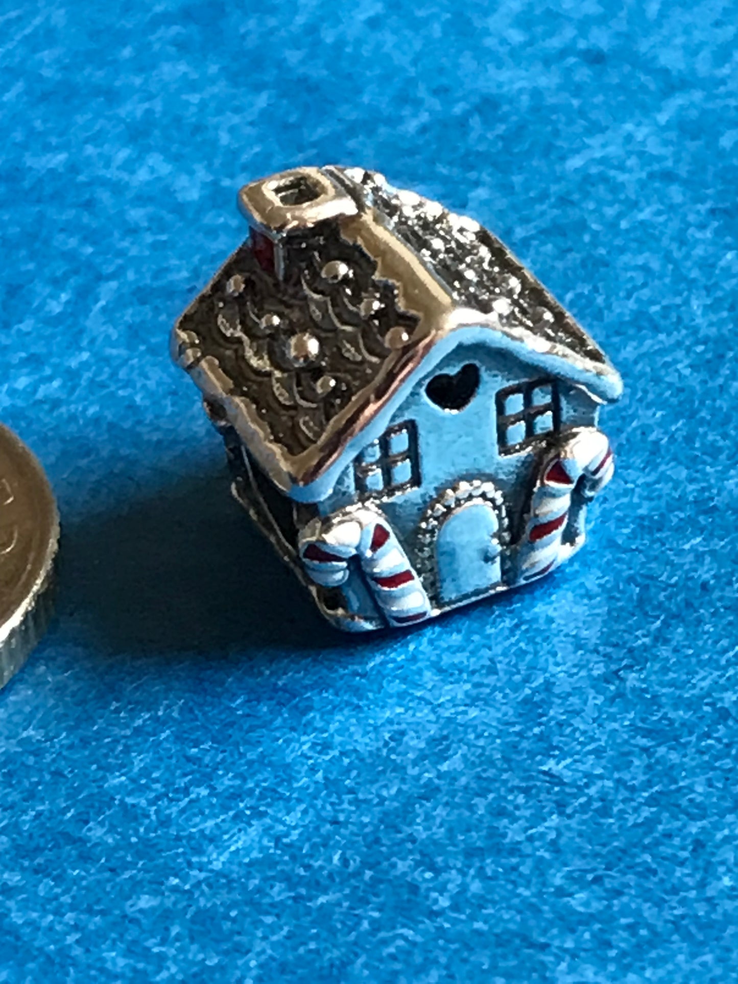 Decorative silver Christmas House charm on a blue background