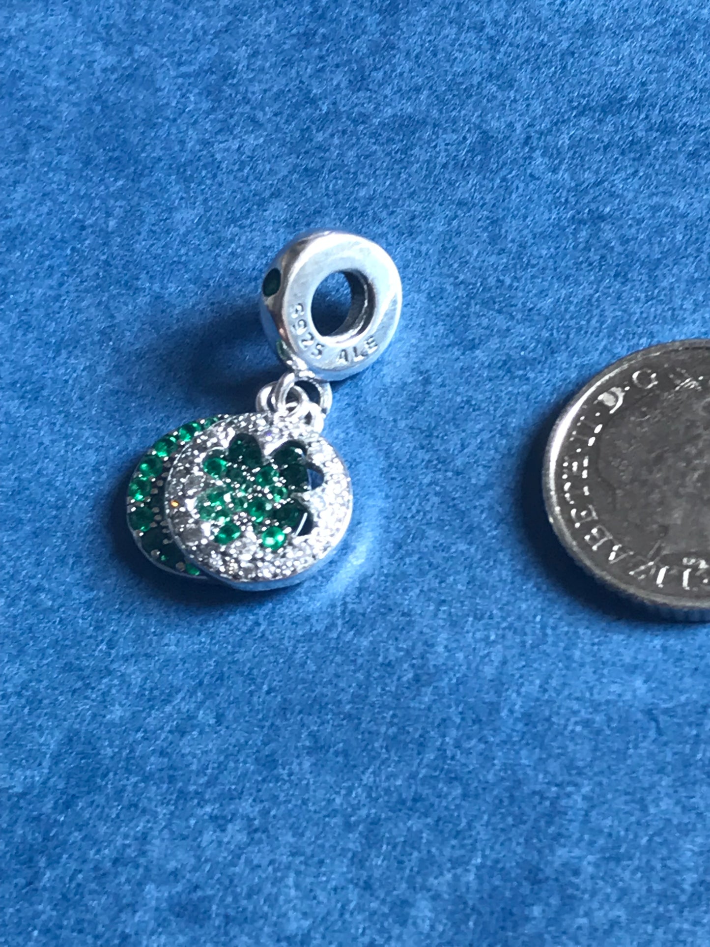 Genuine 925 Silver Green Lucky Clover Charm with green gemstone on a blue background