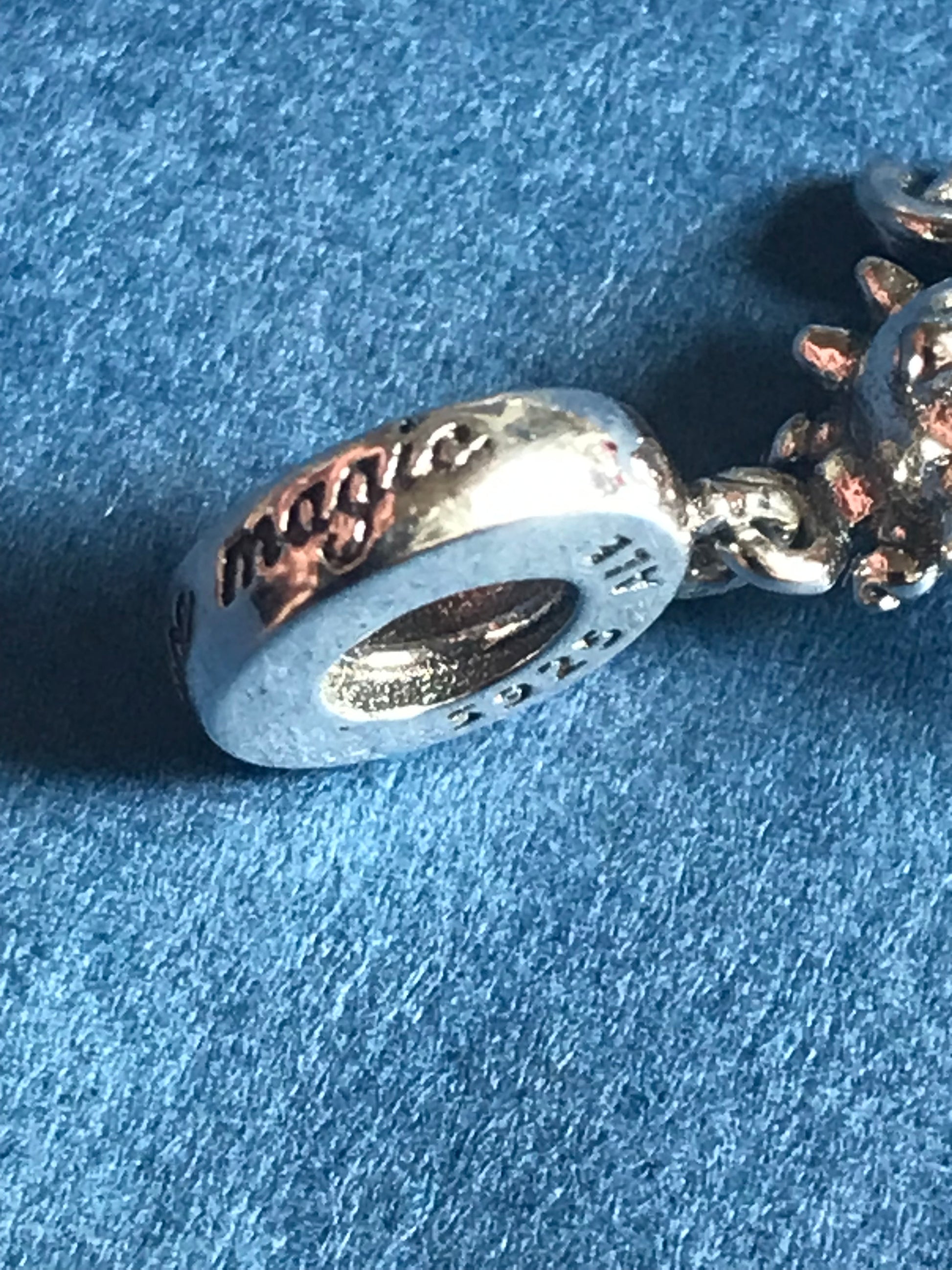 Silver charm with engraved text on a blue textured background