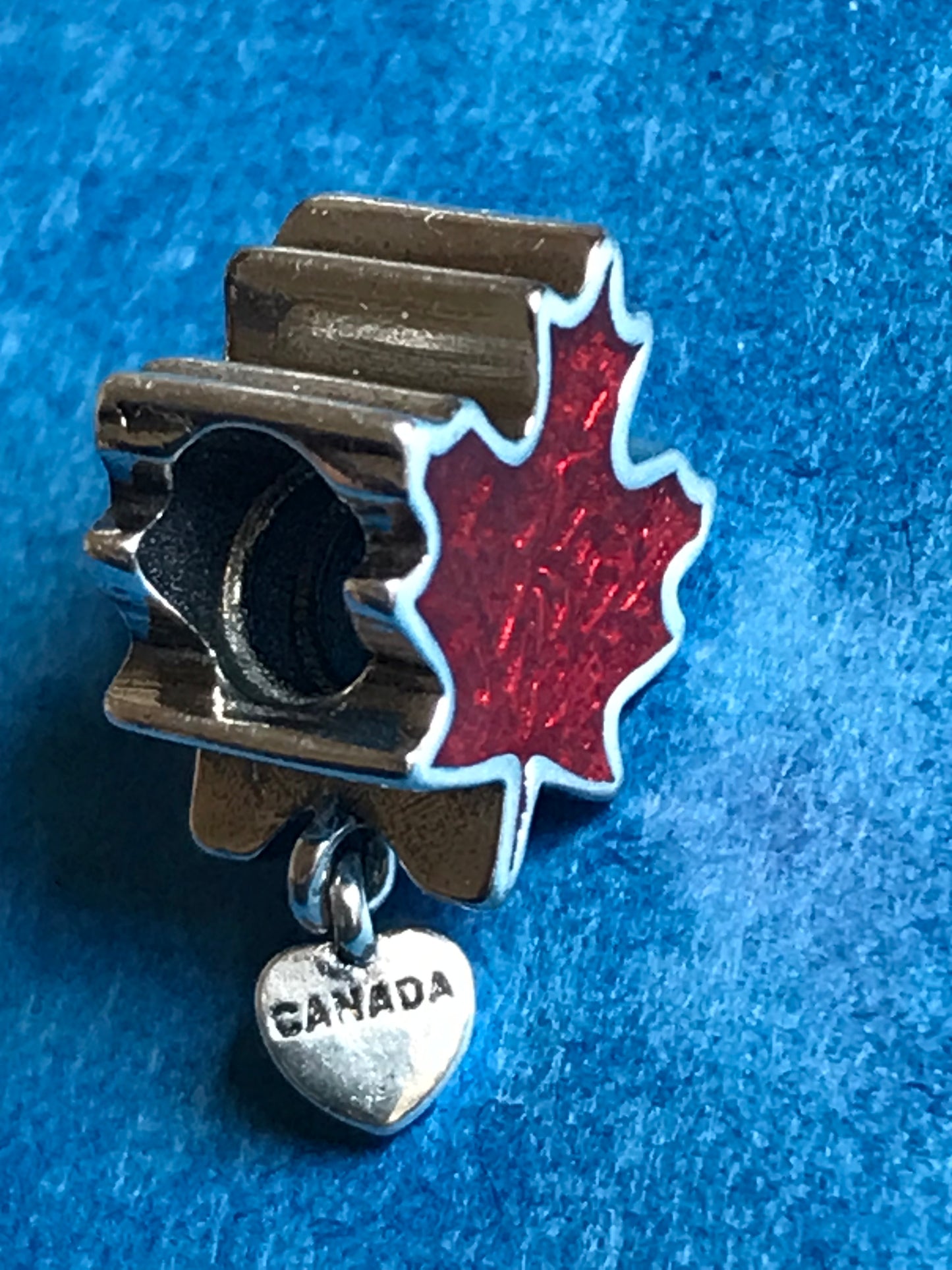 Silver charm with red maple leaf and 'Canada' tag on blue background for charm bracelet 