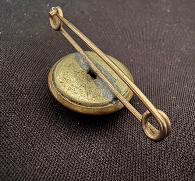 World War Two Trench Art Sweetheart Broach Brass Button on a textured brown background