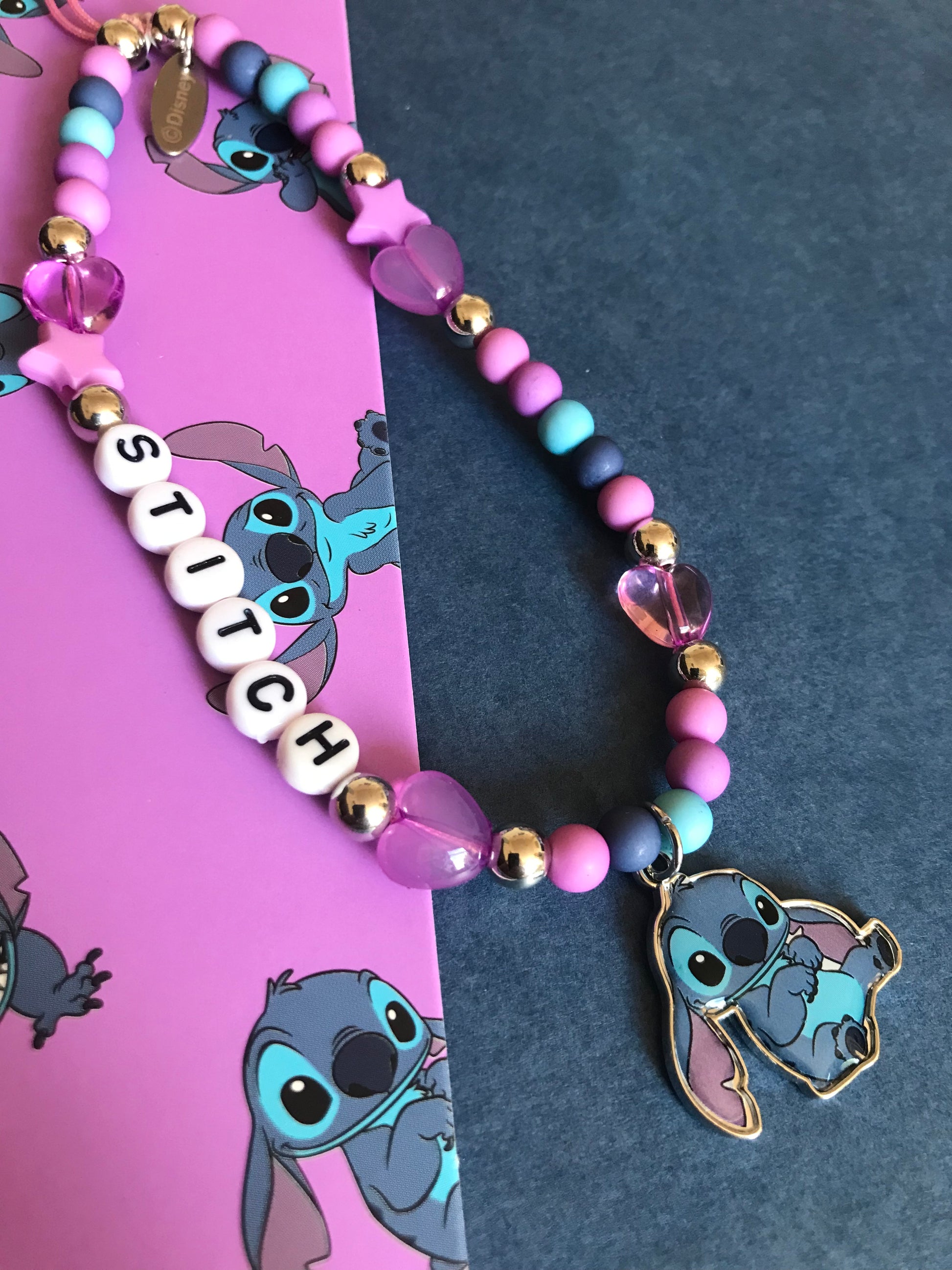 Phone charm with 'STITCH' beads and Stitch character on a dark background
