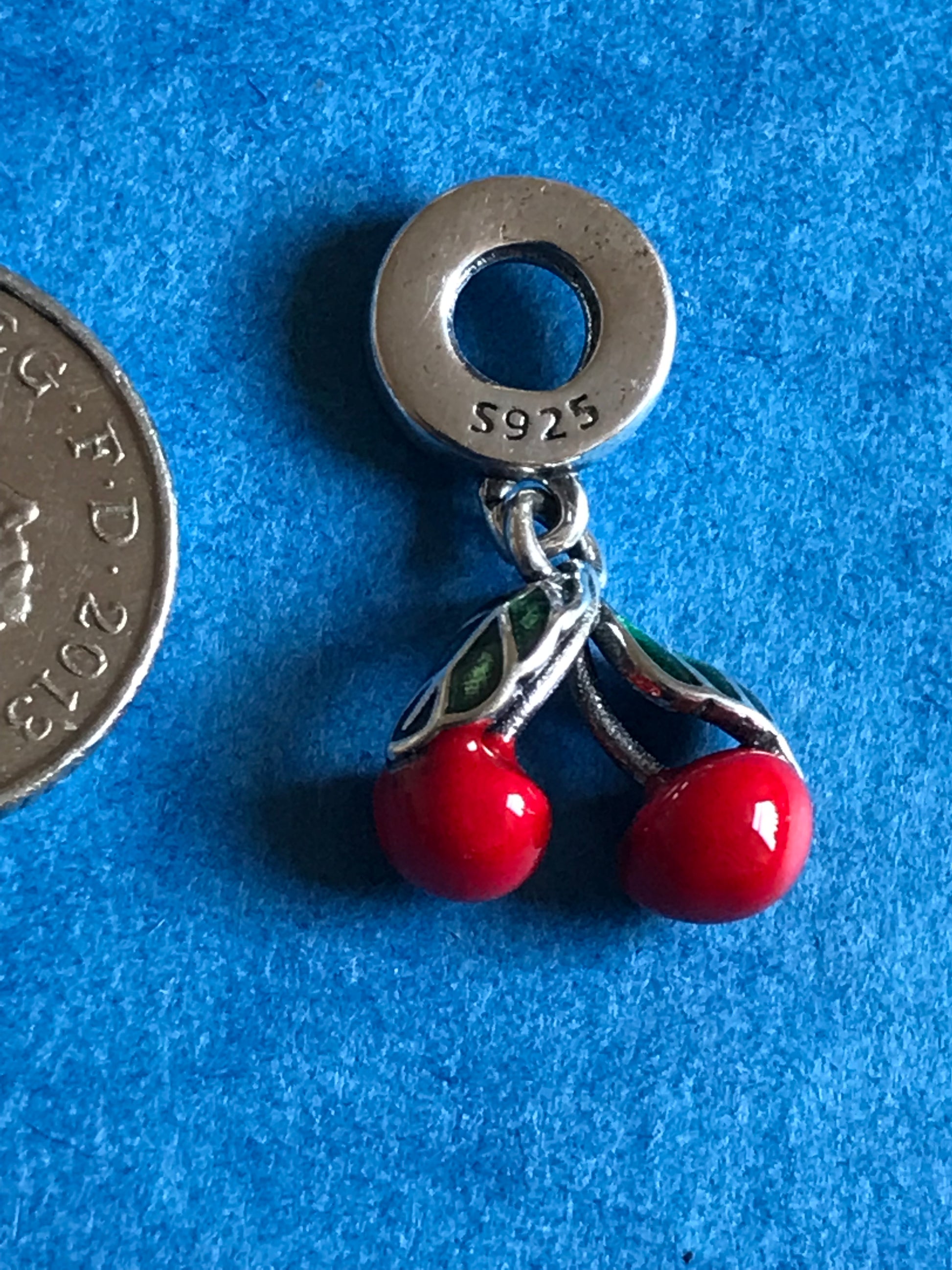 Silver charm with red beads on a blue background