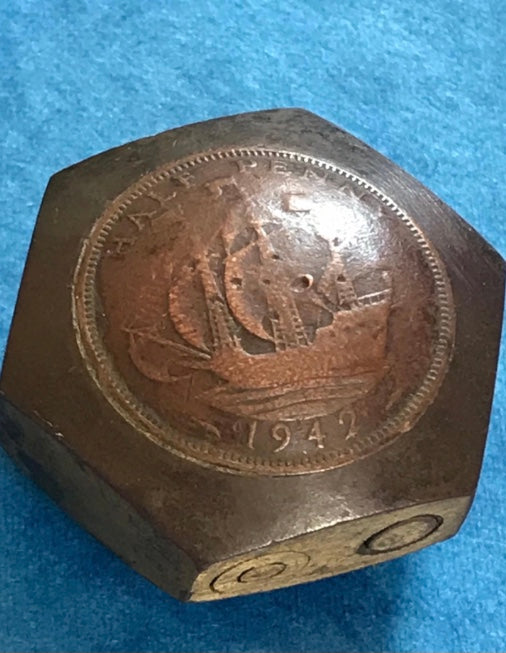 Hexagonal Vintage Genuine WW2 Trench Art 1942 brass lighter with coin design on a blue background