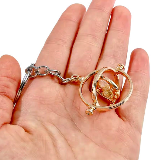 Harry Potter Time Turner Keyring gold colour held in a hand against a white background