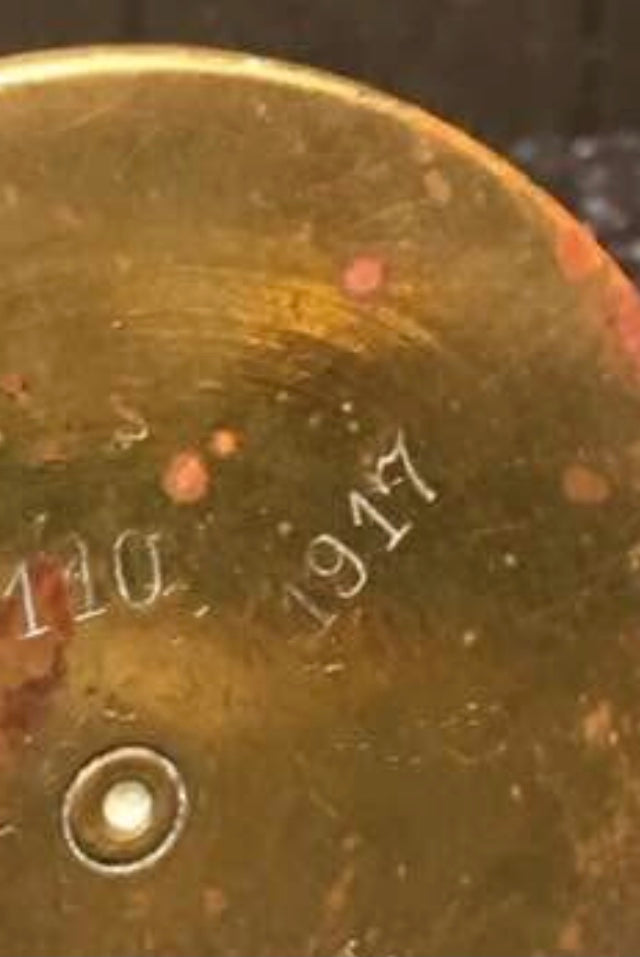 Brass WW1 Trench Art Ashtray with '1917' and '110' inscriptions on a dark background