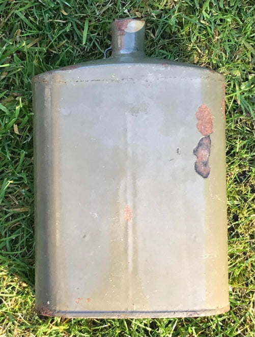 Vintage metal WW2 British Army Water Bottle with rust and wear on grass